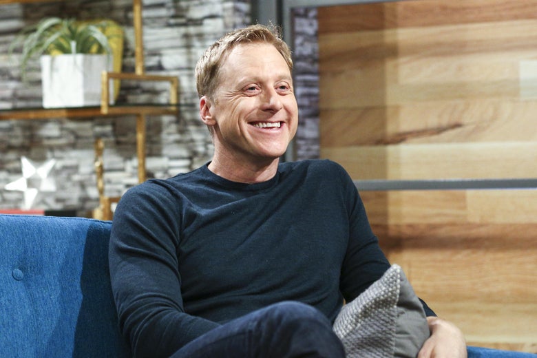 Alan Tudyk sits smiling.